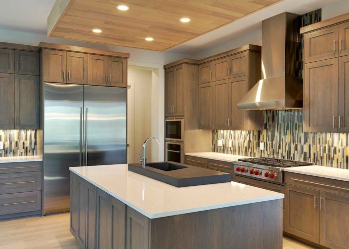 Kitchen with medium ash colored wood cabinets and unique back splash