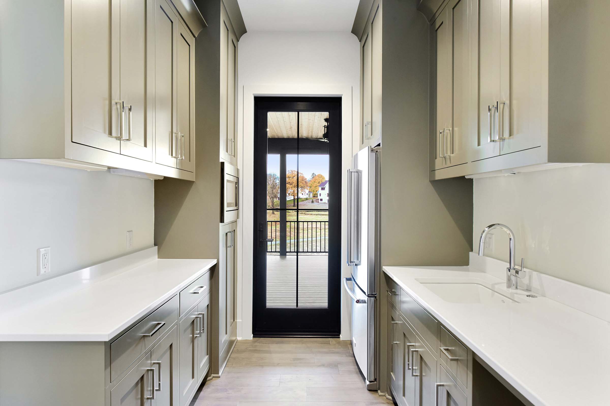 pantry with custom cabinets and door to 3-season screen porch