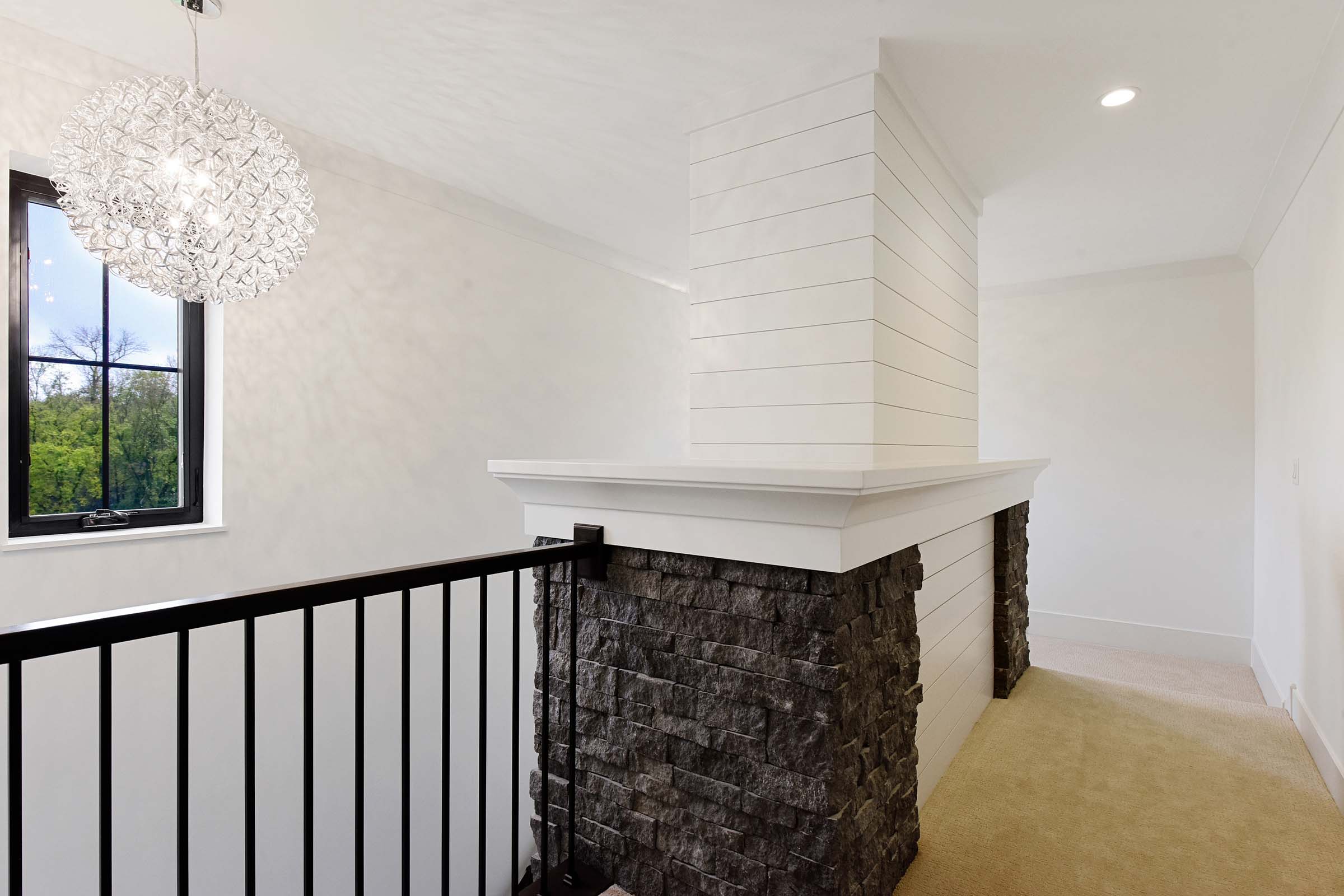 main level stone fireplace extending to second level and staircase with railing