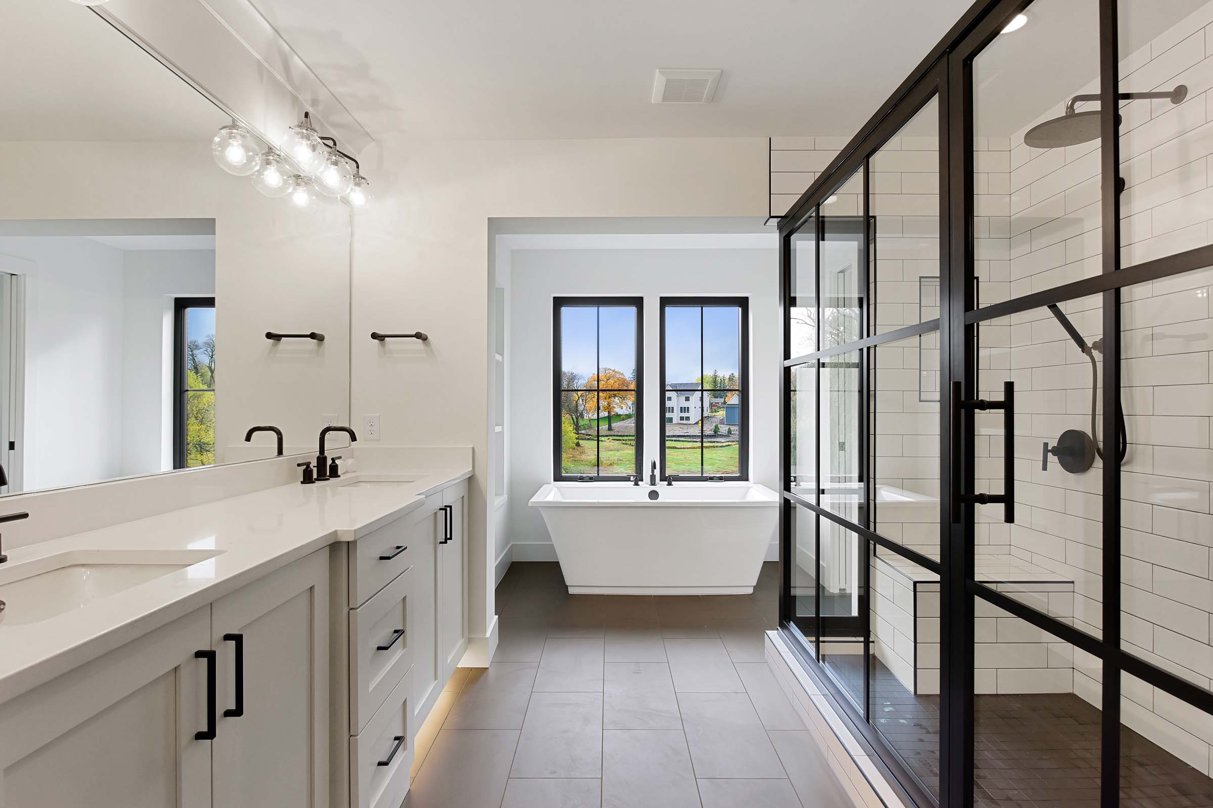 owners bath with freestanding tub and black framed large shower with