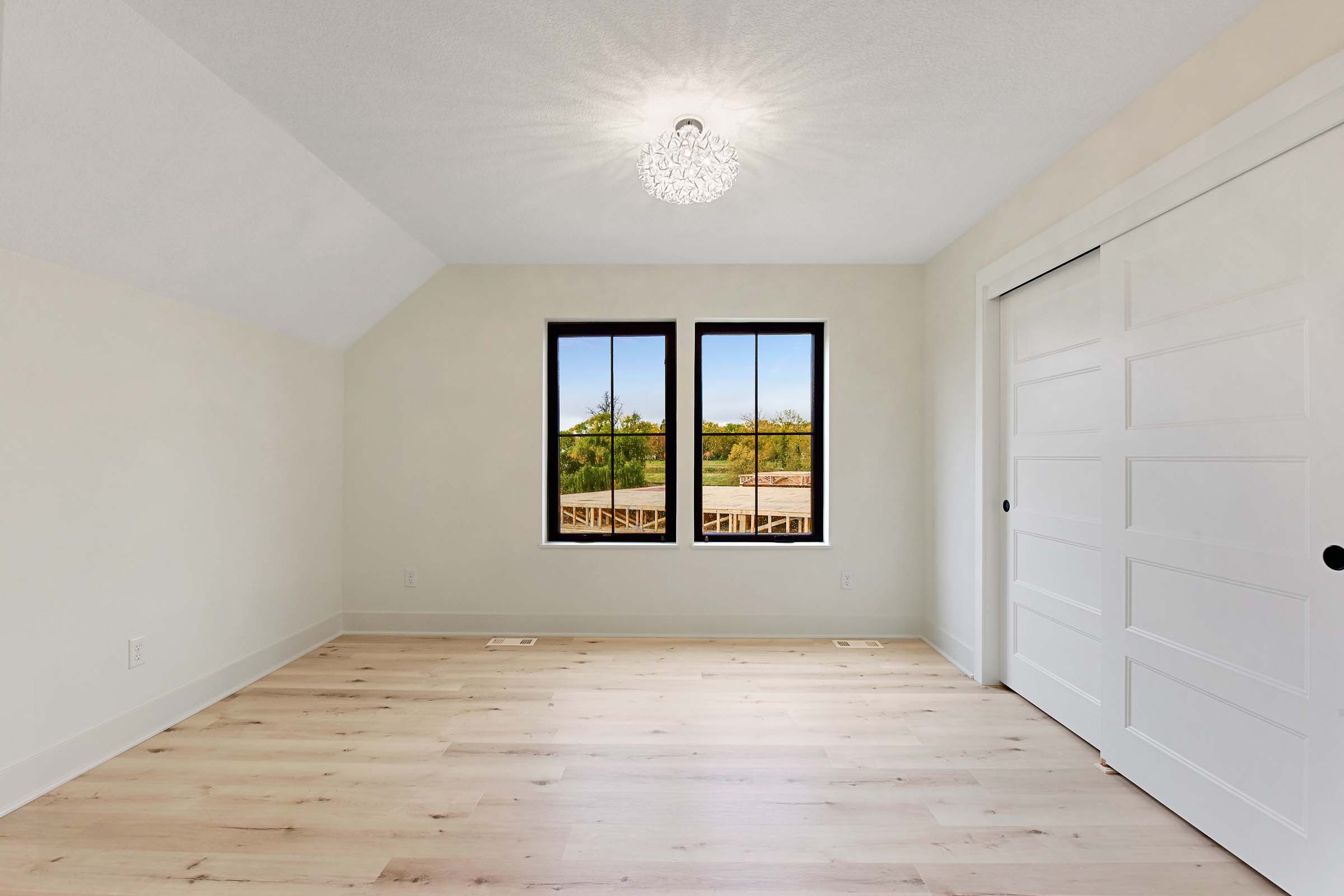 bonus room with two windows and wood flooring above garage